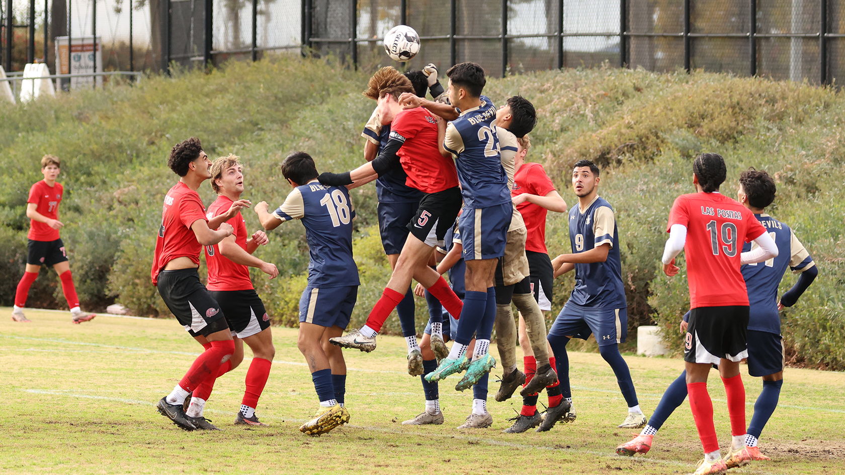 A Hawks goes for a header surrounded by Blue Devils